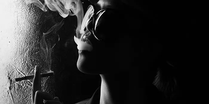 サングラスをかけた女性が煙を吐き出す写真