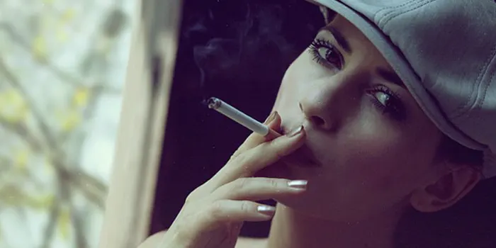 帽子をかぶった女性がたばこをくわえている写真