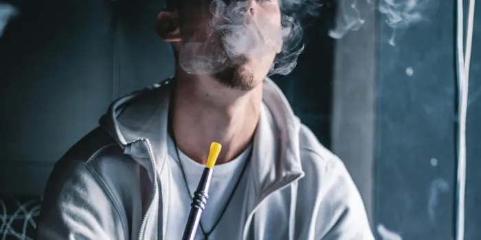 シーシャの煙を吐き出しいている男性の写真